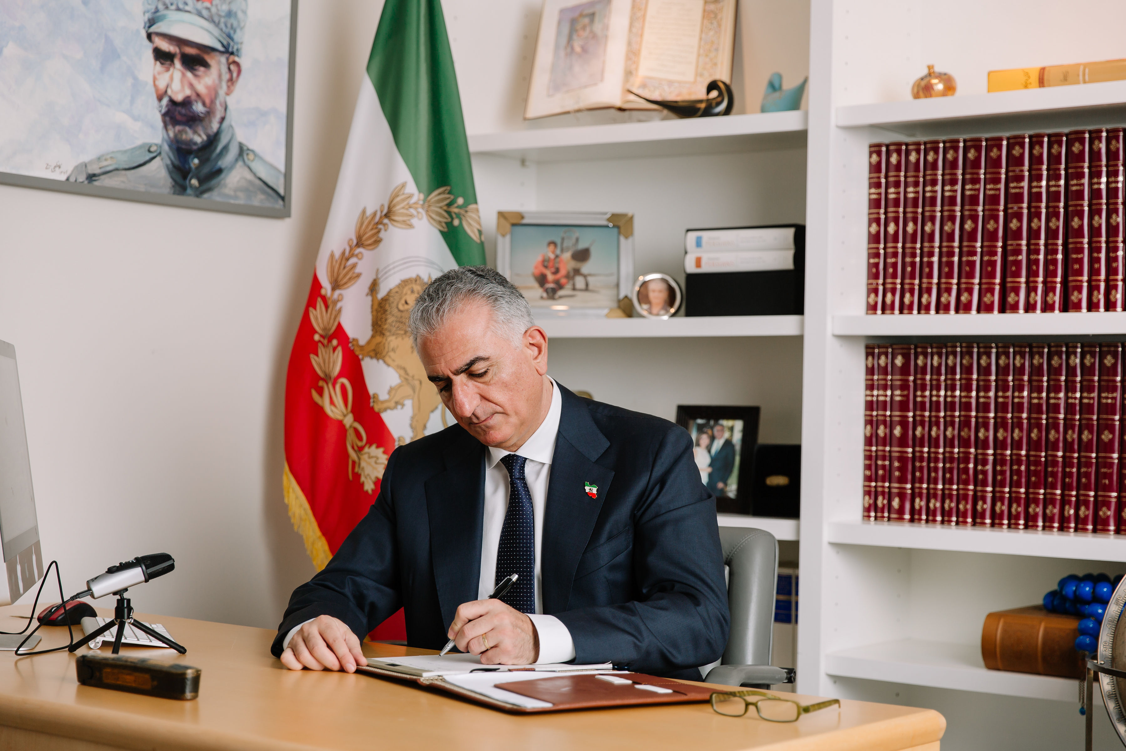 Crown Prince Reza Pahlavi at his desk with the Lion and Sun flag of Iran